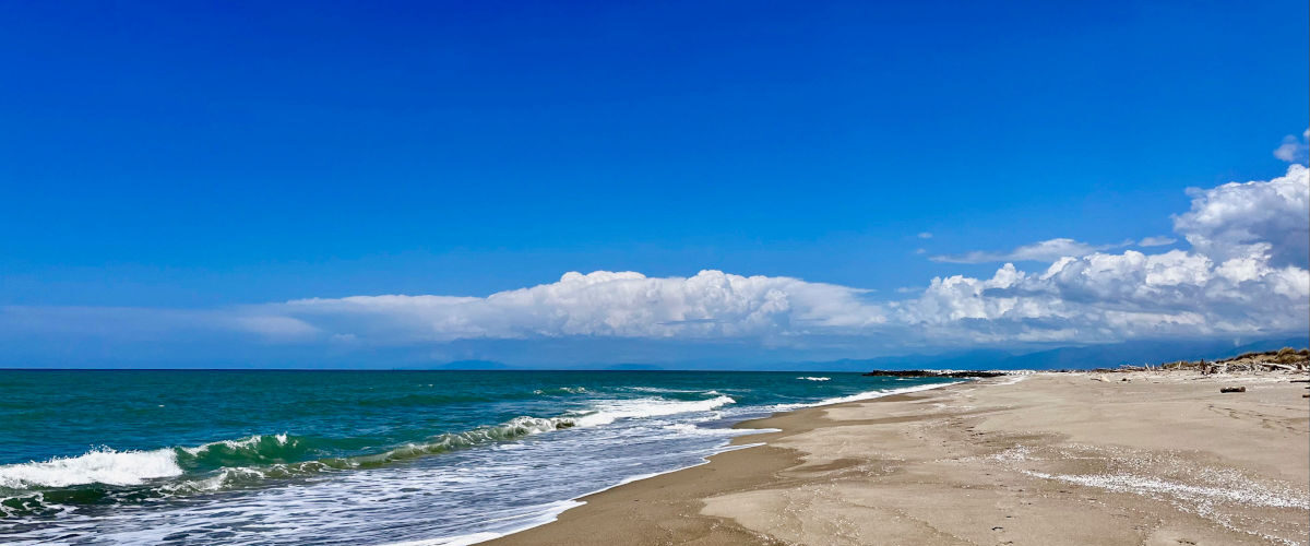 Spiaggia del Gombo nel Parco di San Rossore deserta e selvaggia con cielo azzurro e nuvole bianche. tour guidato zona rossa